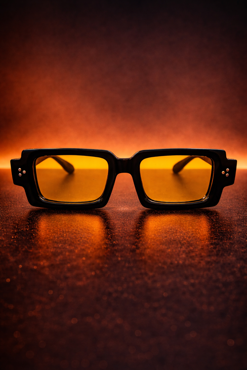 Sunglasses with yellow lenses on a dark surface with a warm glow