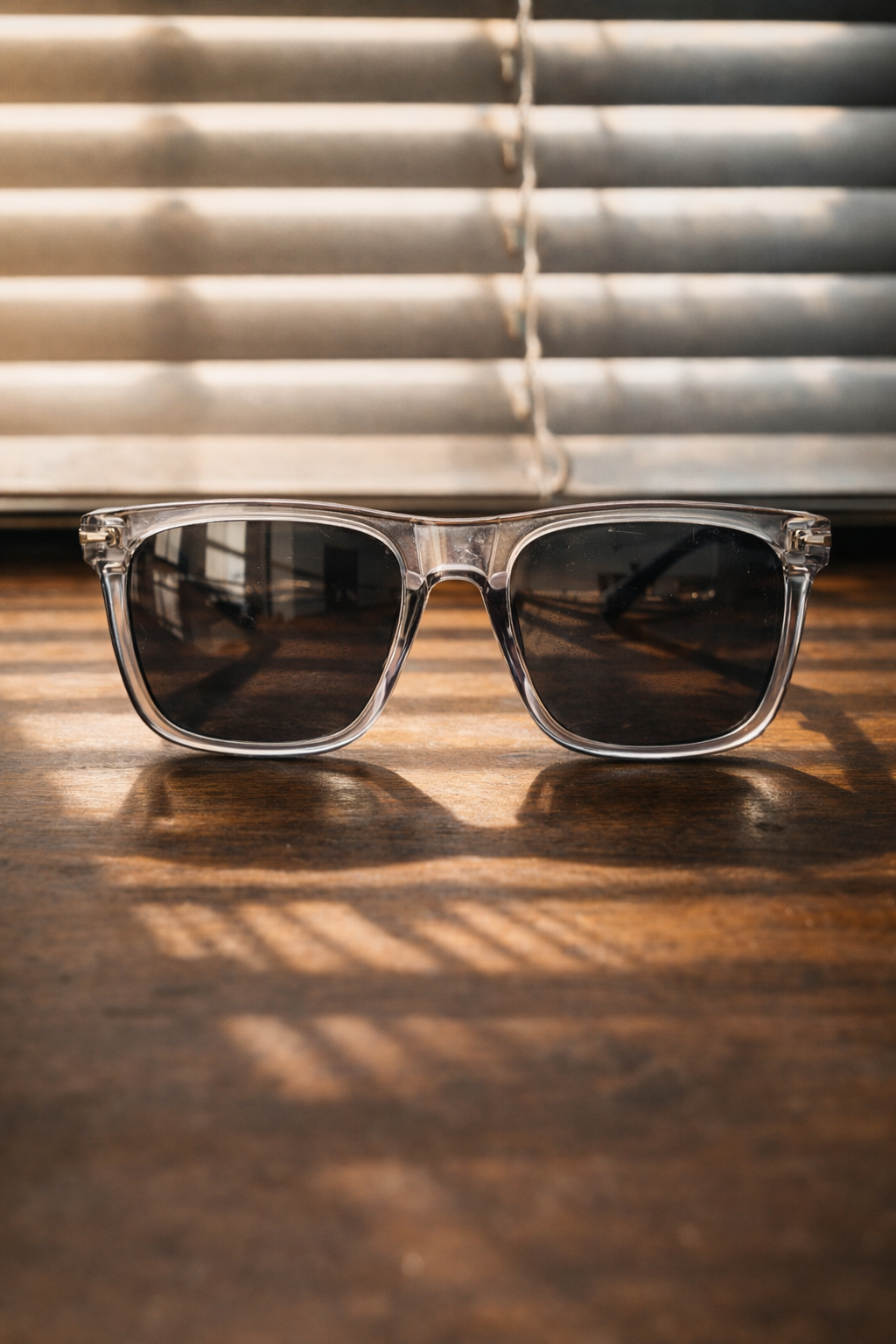 Sunglasses on a wooden surface with blinds in the background