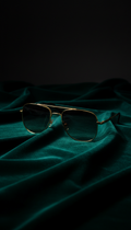 Gold-framed sunglasses on a dark fabric background