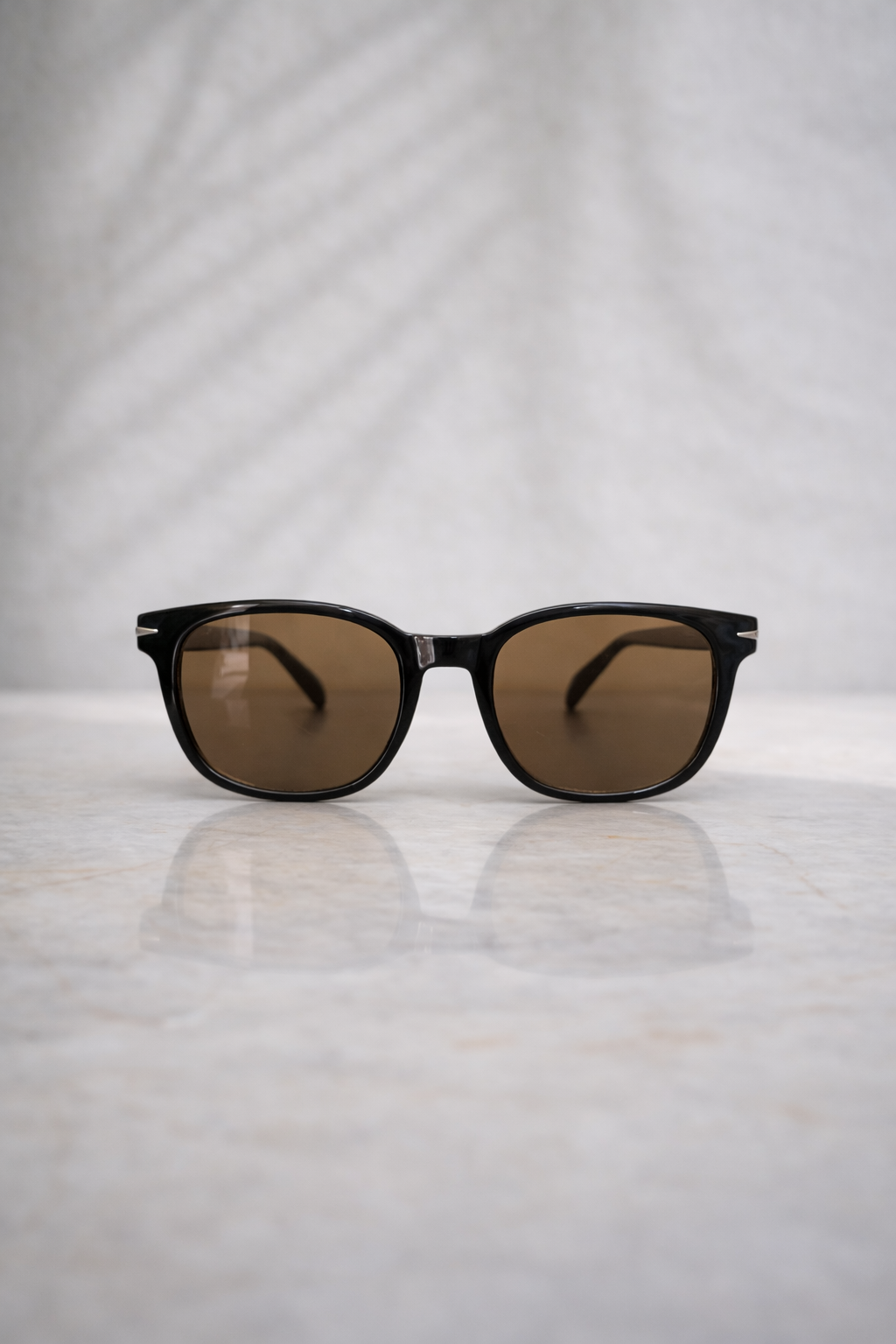 Sunglasses with brown lenses on a reflective surface