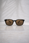 Sunglasses with brown lenses on a reflective surface