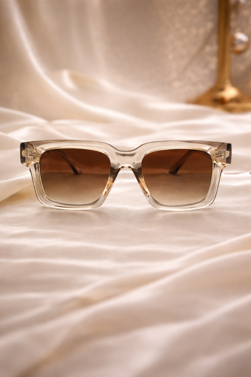 Clear sunglasses with brown lenses on a satin surface