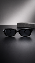 Black sunglasses on a reflective surface with a blurred background