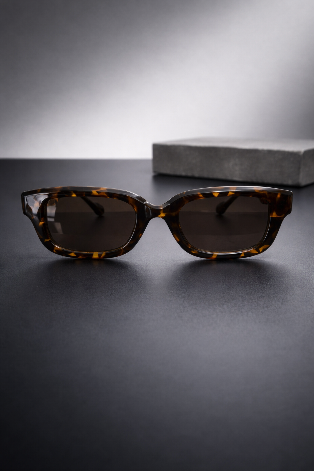 Sunglasses with tortoiseshell frame on a dark surface
